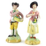 A pair of late 19thC continental porcelain figures of a lady and gentleman, each holding baskets