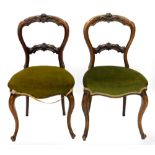 A pair of Victorian rosewood balloon back chairs, each with a padded seat on cabriole legs.