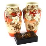 A pair of Japanese Earthenware vases, each decorated with flowers on a mottled coral coloured