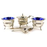 A George V silver three piece cruet, comprising mustard pot and lid and a pair of salts, each with a