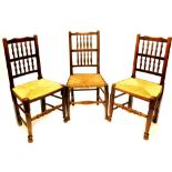 A set of three Lancashire ash spindle back dining chairs, each with a rush seat on turned tapering