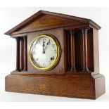 An early 20thC oak and marquetry portico shaped mantle clock, the enamel type dial with Arabic