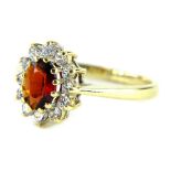 A 9ct gold dress ring, with central garnet surrounded by white stones, ring size N, 2.4g all in.