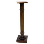 A mahogany torchere or plant stand, with a square top on a turned and fluted column, and square