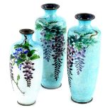 A pair of Japanese cloisonne vases, each decorated with wisteria in purple and pink, with green