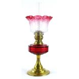 A late 19th/early 20thC oil lamp, with a part cranberry tinted shade, a ruby tinted reservoir and