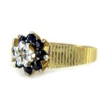 A 9ct gold floral cluster ring, set with eight sapphires and a tiny diamond to centre, with etched