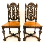 A pair of Victorian carved oak hall chairs, each with a pierced back, a solid seat, on turned legs