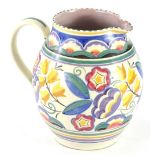 A Poole pottery jug, decorated in typical fashion with flowers and leaves in yellow, blue, green,