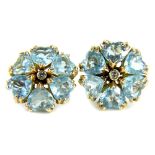 A pair of aquamarine and diamond earrings, each set in a floral cluster with central diamond