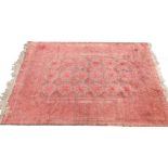 A Turkman carpet, with a design of medallions, on a deep red ground with one wide and multiple