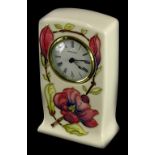 A Moorcroft pottery mantel clock, decorated with pink and purple flowers, on a cream ground,