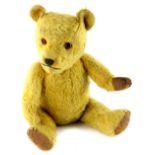 An early 20thC teddy bear, with worn canvas pads, with a straw type filling, 42cm high.