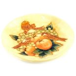 A Moorcroft pottery plaque, decorated with fruit, birds, in shades of brown, beige and green,