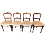 A set of four Victorian walnut balloon back dining chairs, each with a shell carved back, a padded