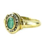 A 9ct gold emerald and diamond dress ring, set with oval cut emerald in rub over setting, surrounded