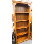 A Jig style hardwood open bookcase, of rectangular form, with fixed moulded cornice, raised above