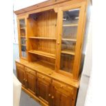 A 20thC pine dresser, with fixed moulded cornice, raised above two open shelves, flanked by glazed
