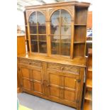 An Old Charm style oak display cabinet, with glazed doors, raised above two frieze drawers, and