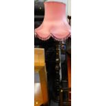 A 20thC lamp stand with pink shade, on a turned baluster stem, terminating in a stepped circular