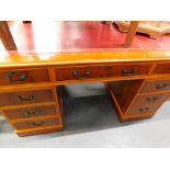 A 20thC yew wood twin pedestal desk, with tooled red leatherette top, raised with three frieze