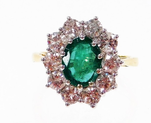 An 18ct gold emerald and diamond cluster ring, with oval cut emerald 8.6mm x 6.6mm x 3.8mm, totallin