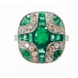 An Art Deco style emerald and diamond ring, with central oval cut emerald and further baguette cut e