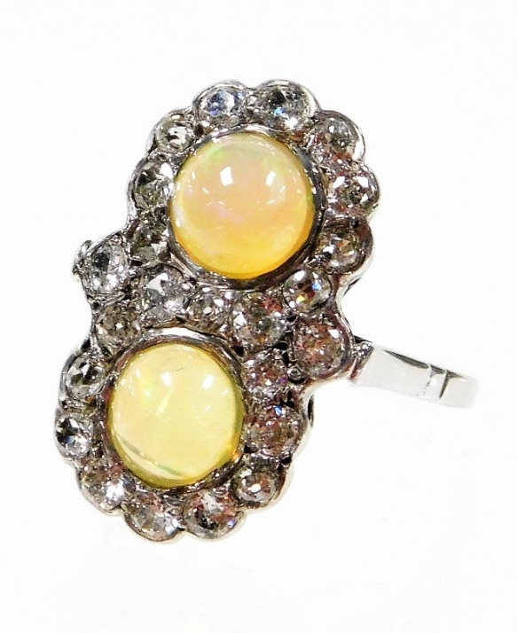 A Victorian opal and diamond dress ring, with two opals, surrounded by old cut diamonds, the ring he