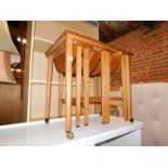 A teak quartetto of folding tables, raised on castors, 57cm high, 62cm wide, 42cm deep.