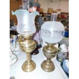 Two brass oil lamps, with chimneys and frosted glass shades, 59cm high and 52cm high respectively.