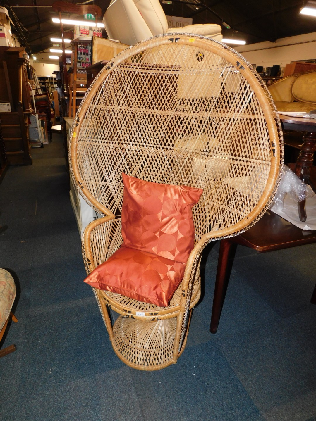 A cane peacock chair with loose cushion.