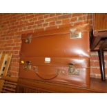 Two brown leatherette suitcases, largest 23cm high, 60cm wide, 23cm deep.