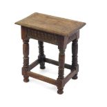 A 17thC style oak coffin stool, raised on turned legs united by a box stretcher.