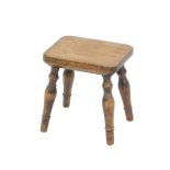 An oak and elm milking stool, raised on turned legs, engraved to underside of seat 'Woodstock', 25cm