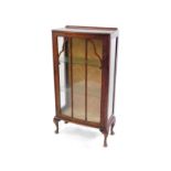 An early 20thC walnut display cabinet, with glazed sides and door, opening to reveal two glass