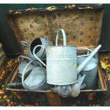 A black metal trunk, brass bound, containing seven galvanized metal watering cans, one and a half