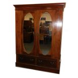 An Edwardian mahogany and inlaid double wardrobe, the outswept pediment over two doors, inset oval