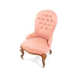 A Victorian walnut spoon back nursing chair, upholstered in button back pink floral fabric, raised