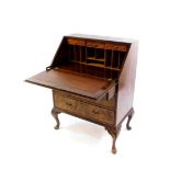 An early 20thC walnut and mahogany bureau, the fall flap opening to reveal drawers and recesses,
