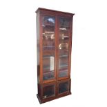 A Victorian and later mahogany bookcase, the outswept pediment over a pair of glazed doors opening