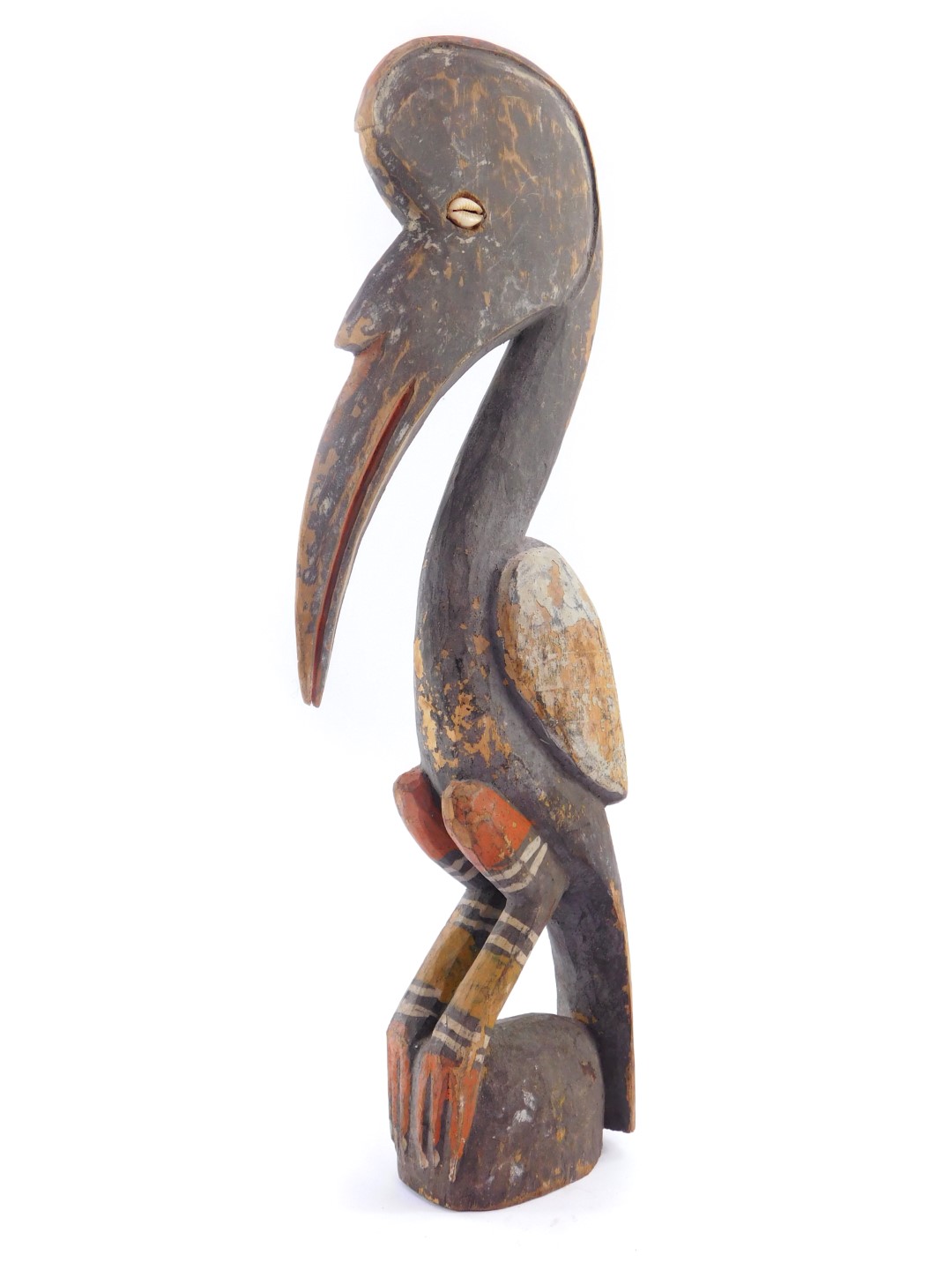 A Papua New Guinea Sepik carving of a bird, the eyes set with a shell, grey and red paint pigments