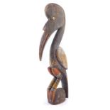 A Papua New Guinea Sepik carving of a bird, the eyes set with a shell, grey and red paint pigments