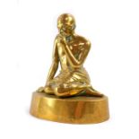 A brass figure of Mahatma Gandhi, modelled kneeling on an oval base, 20cm high.