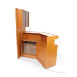 A Turnidge of London teak corner bar, with a serving counter, over a shelf, above two glazed doors