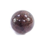 A Mozambique veined and dappled granite ball, shades of purple and grey, 10cm diameter.