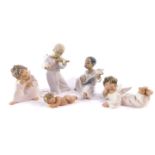 Four Lladro porcelain figures modelled as cherubs, two modelled in contemplation, one playing a