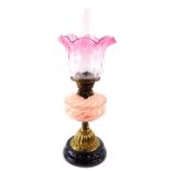 A Duplex early 20thC brass oil lamp, with a pink clear and pearlescent glass reservoir, glass