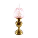 An early 20thC brass oil lamp, with a glass chimney and pink honeycomb glass shade, 53cm H.