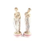 A pair of Continental late 19thC bisque figures modelled as Roman ladies, in standing pose, raised