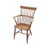 A 19thC oak and elm comb back Windsor chair, with solid saddle seat, raised on turned legs united by